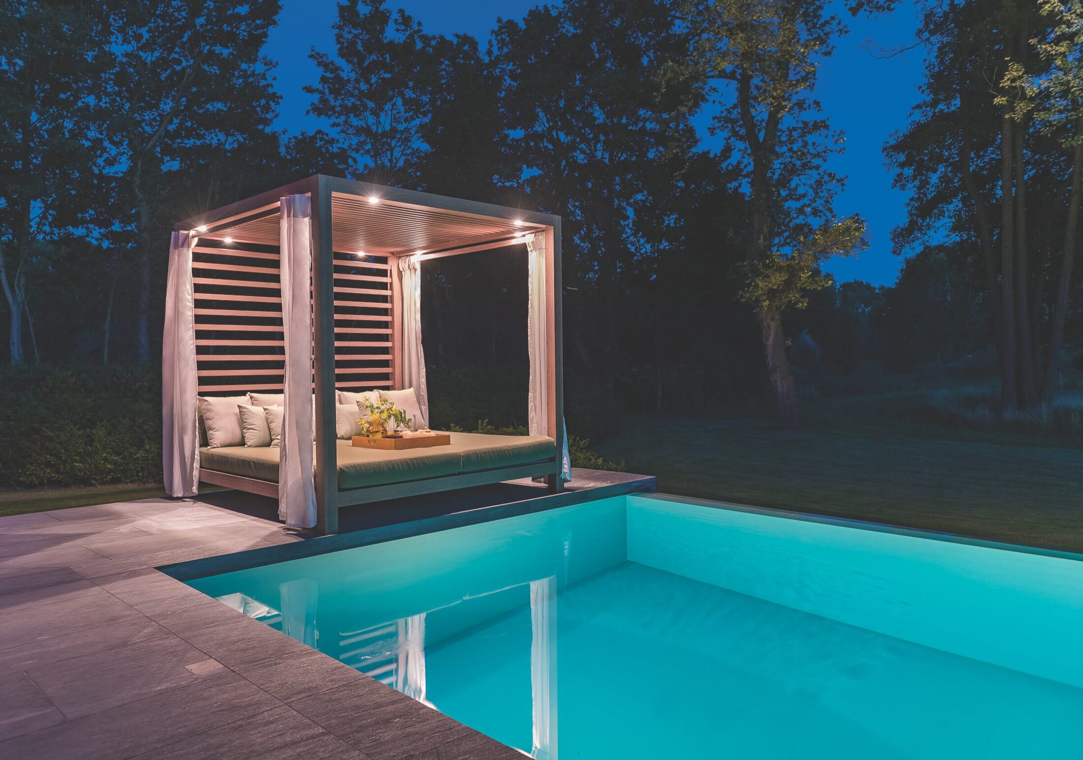 A Tuuci MAX Solanox cabana beside a pool at dusk